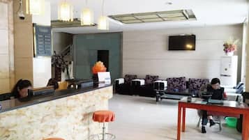 Un hall de hotel con mostrador de recepción, zona de estar y una escalera.