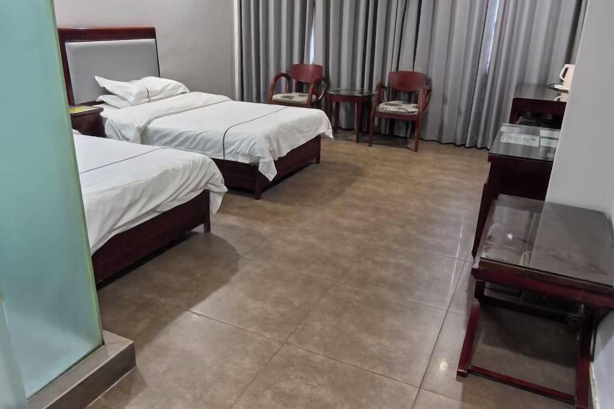 A hotel room with two beds, a desk, and two chairs.