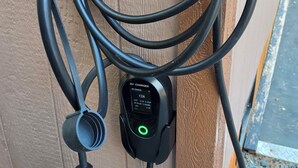 An EV charger connected to a wooden post with a clear plastic cover.
