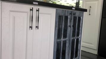 A modern kitchen with white cabinetry, a black countertop, and a glass-enclosed island.