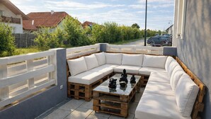 A modern outdoor seating area with a white cushioned sectional sofa and a wooden coffee table.