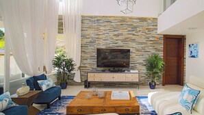 Un salon moderne avec un mur en pierre, un téléviseur à écran plat et une table basse en bois.