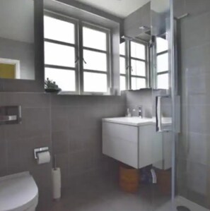 Une salle de bain moderne équipée de toilettes, d’un lavabo et d’un espace douche.