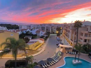 Ein Resort mit Pool, mehrstöckigen Gebäuden und Blick auf den Sonnenuntergang.