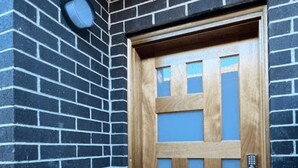 Una puerta de madera con paneles de vidrio, incrustada en un muro de ladrillo.