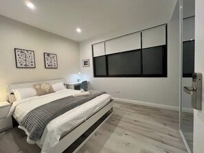Ein modernes Schlafzimmer mit Bett, Nachttischen und einem Kleiderschrank.