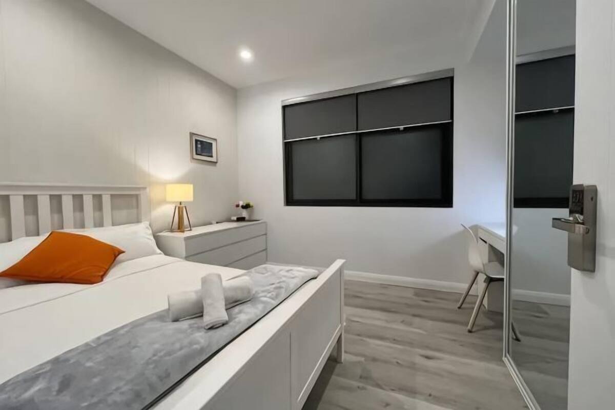 A modern bedroom with a bed, bedside table, and a desk.