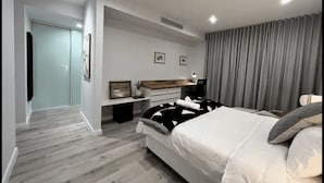 Un dormitorio moderno con una cama grande, una mesita de noche, un aparador y un vestidor.