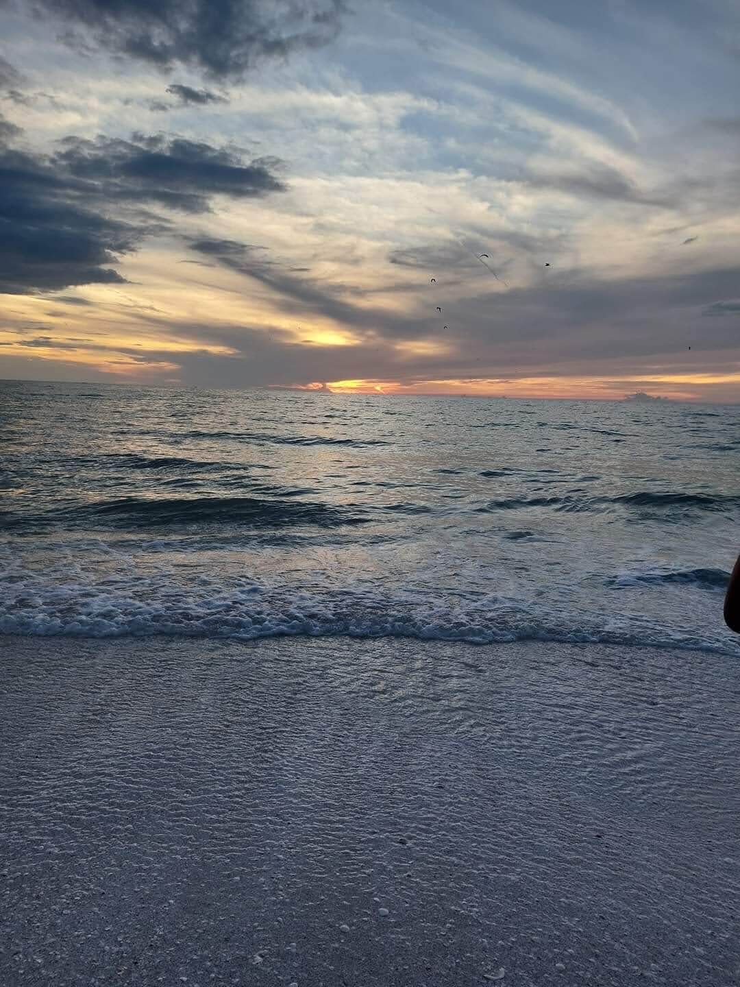 A beach with waves and a sunset.