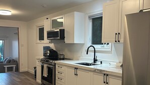 Eine moderne Küche mit weißen Schränken, einem Edelstahl-Kühlschrank, einer Mikrowelle und einem Gasherd.