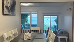 Ein Essbereich mit Blick auf das Wasser, ein Gemälde an der Wand und ein Deckenrauchmelder.