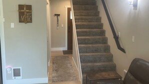 Una escalera que lleva al segundo piso, un sofá de cuero y un tapete estampado en una sala de estar.