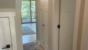 Un pasillo con puertas blancas, alfombra gris y suelo de madera.