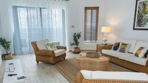 Een woonkamer met een bank, fauteuil, salontafel en bijzettafeltje met een lamp.