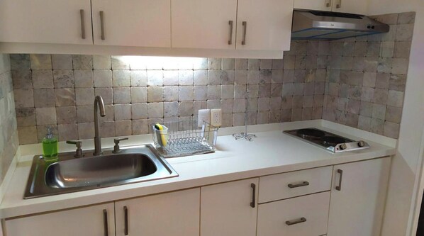 A kitchen with a stainless steel sink, a dish rack, and a stove.
