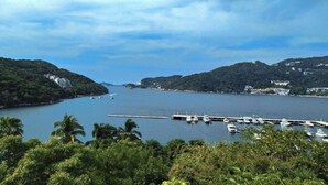 A marina with boats docked, surrounded by lush greenery and hills.