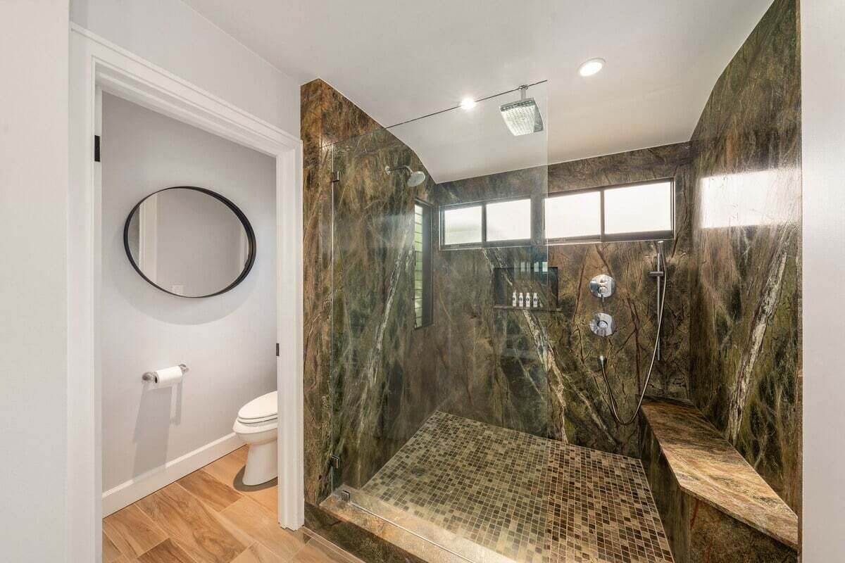 Een moderne badkamer met een glazen douchecabine, toilet en wastafel.