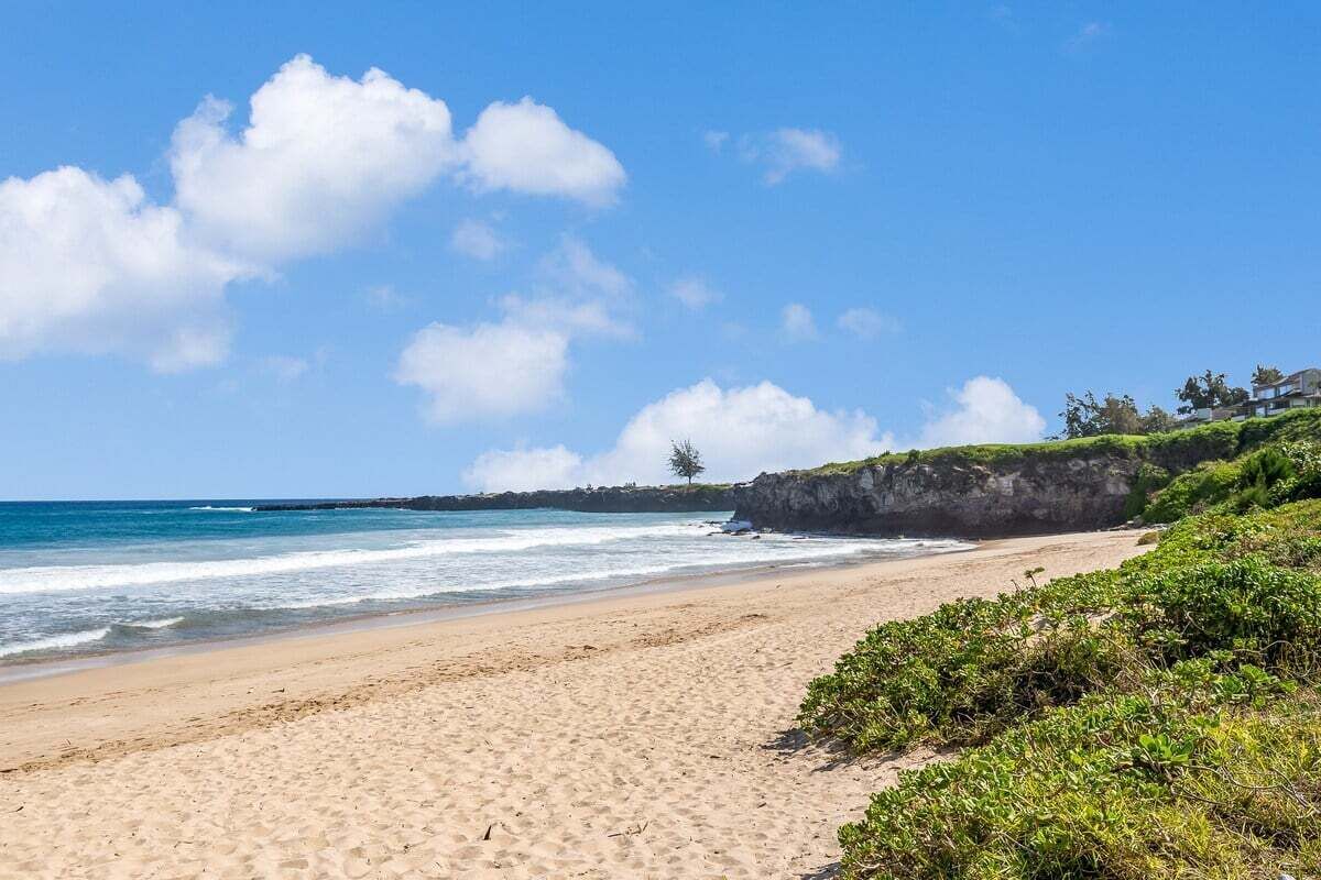 Ein Strand mit blauem Himmel und ruhigem Wasser.