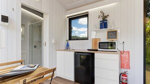 A compact kitchen with a microwave, sink, and a fire blanket on the wall. - Tiny Sublime by Tiny Away (Kia Ora)