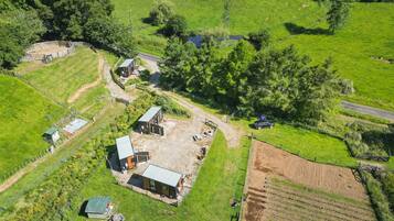 Luchtbeeld van een landgoed met meerdere gebouwen, omheinde stukken grond en een onverharde weg.