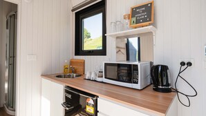 A compact kitchen with a built-in dishwasher, a microwave, and a coffee maker. A window above the sink offers a view of the outdoors.