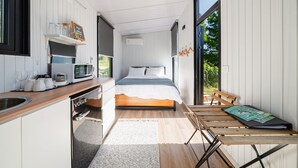 A compact bedroom with a bed, bedside table, and a window.