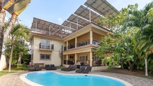 A two-story building with a swimming pool, sun loungers, and a covered patio area. - Twin Villas Perfect for Group Trips (Sosúa)