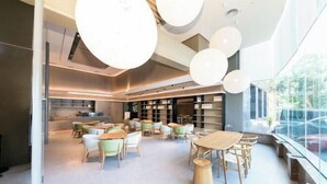 A modern interior with a dining area featuring round tables and chairs, a kitchen in the background, and large windows providing natural light. - JI Hotel (Fuzhou Yantaishan Park Shangsan Road) (Fuzhou)