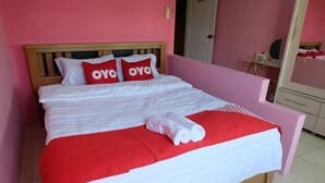 A bed with a wooden headboard, two red pillows, a white blanket, and a red and white bedspread. - OYO 75429 '101 Place Navanakorm' (Khlong Luang)