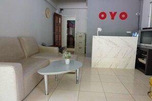 A living room with a sofa, a coffee table with a flower, a kitchen area with a marble counter, and a wall with the word 'OYO'. - OYO 75429 '101 Place Navanakorm' (Khlong Luang)
