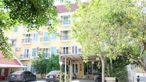 A multi-story building with balconies, a covered entrance, and parked cars. - OYO 75429 '101 Place Navanakorm' (Khlong Luang)