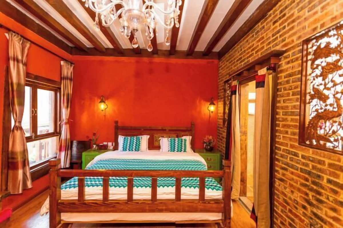 A room with a wooden bed, a chandelier, and a brick wall.