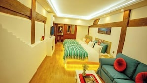 A hotel room with a wooden staircase, a sofa, a bed with a green and white striped bedspread, and a painting on the wall. - Good Journey Inn (Shangri-La Guangdong Club) (Shangri-La)