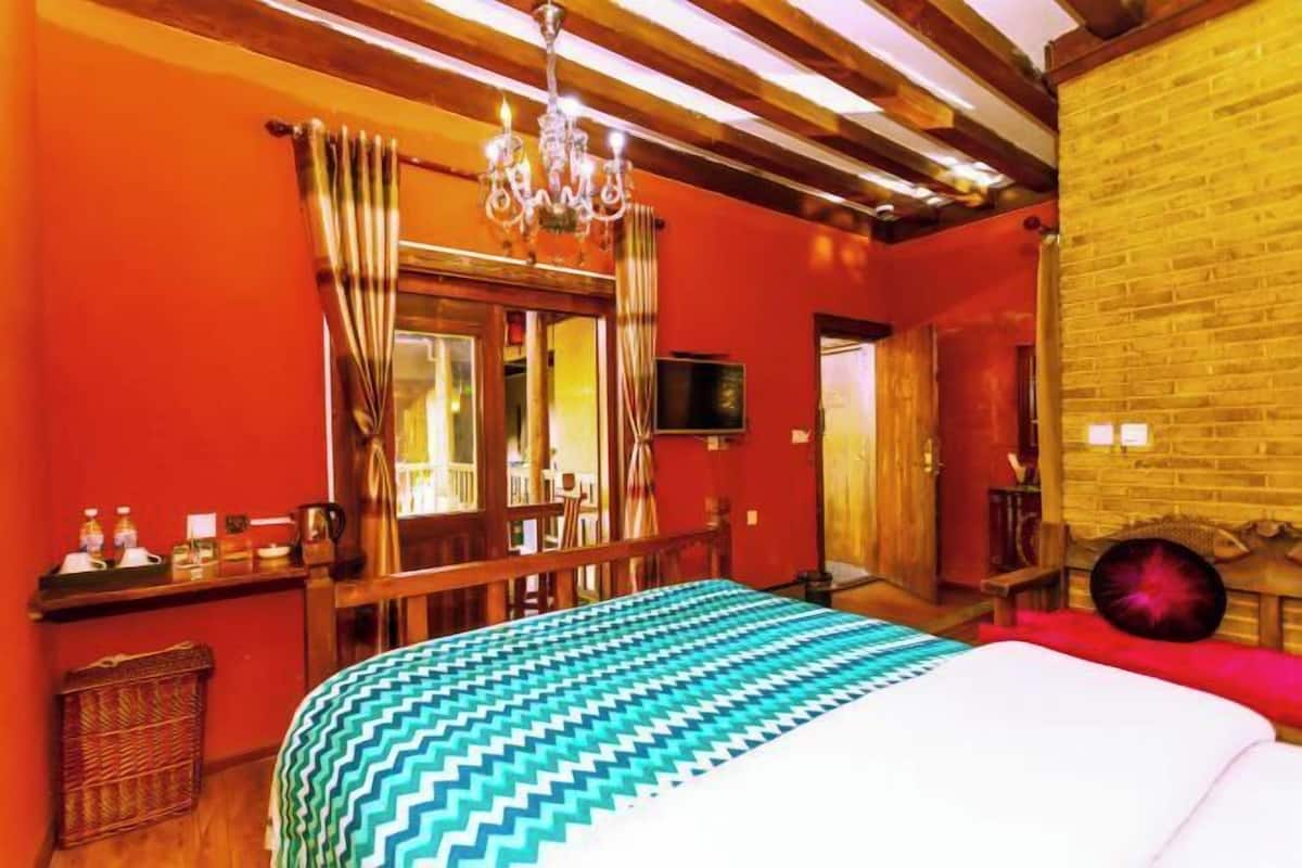 A room with a bed, a chandelier, a wooden ceiling, and a brick wall.
