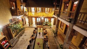 A traditional courtyard with a long dining table and benches, surrounded by wooden buildings with balconies. - Good Journey Inn (Shangri-La Guangdong Club) (Shangri-La)