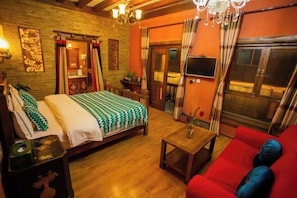 Une pièce confortable avec un lit, un canapé rouge, une table basse en bois et un téléviseur.