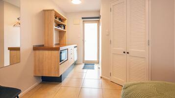 A hallway with a wooden cabinet, a microwave, and a door leading to a room.