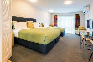 A hotel room with two beds, a desk, a chair, a television, and a window with curtains. - Tussock Peak Lodge (Hanmer Springs)
