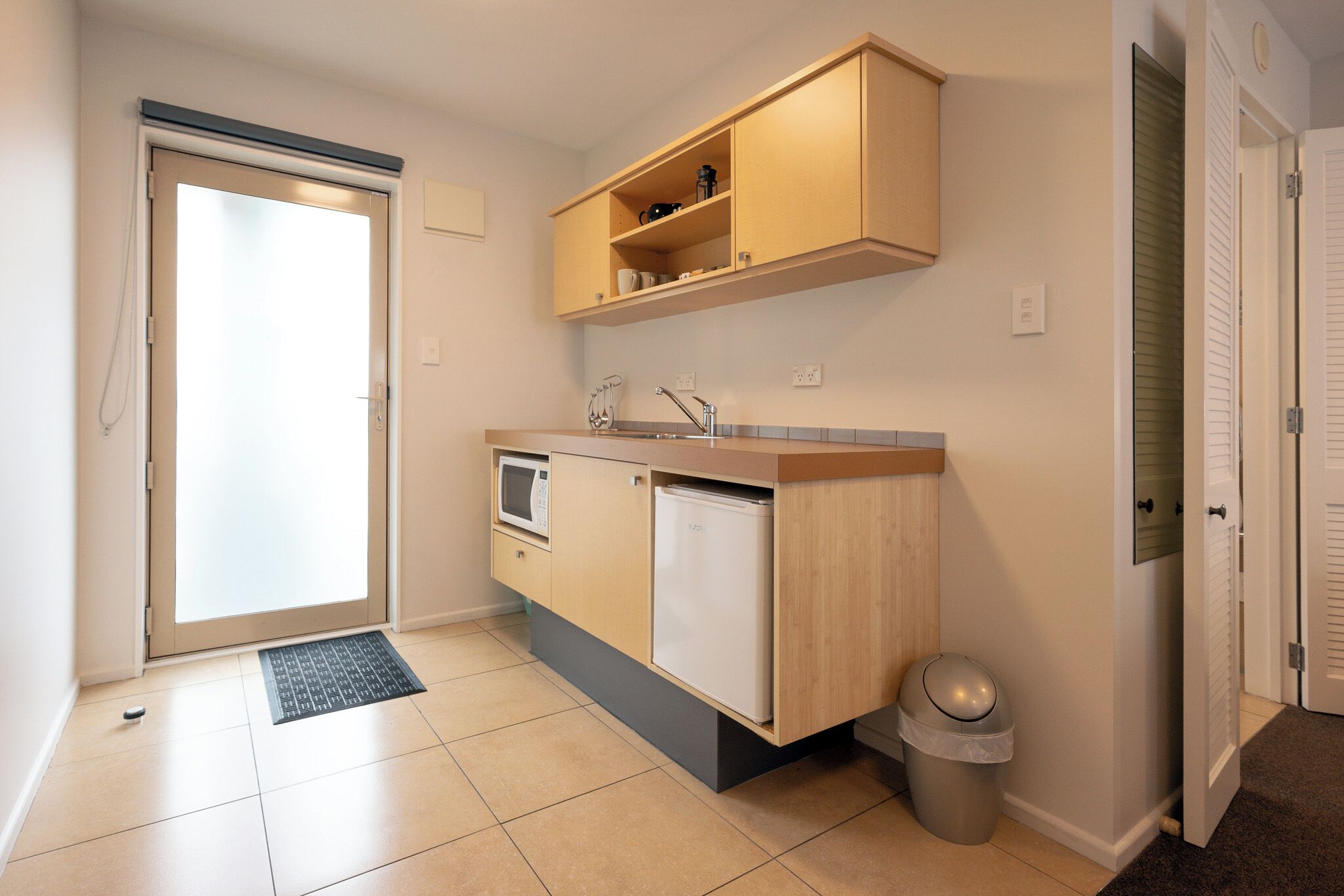 A compact kitchen with a microwave, sink, and storage cabinets.
