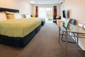 A hotel room with a bed, a desk, a chair, a TV, and a view of the outdoors. - Tussock Peak Lodge (Hanmer Springs)