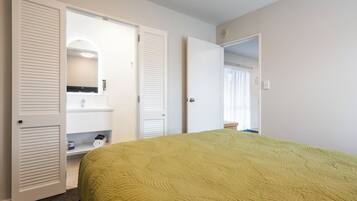 Una habitació d'hotel amb un llit, un bany amb un lavabo i un mirall, i dues portes que donen a altres habitacions.
