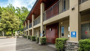 A hotel with a covered outdoor area, stone pillars, and a sign indicating electric vehicle charging is available. - Tussock Peak Lodge (Hanmer Springs)