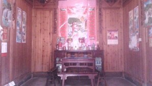 A room with wooden walls, a central table with chairs, and artwork on the walls. - Qingyuan Renjia Inn (Wuyuan)
