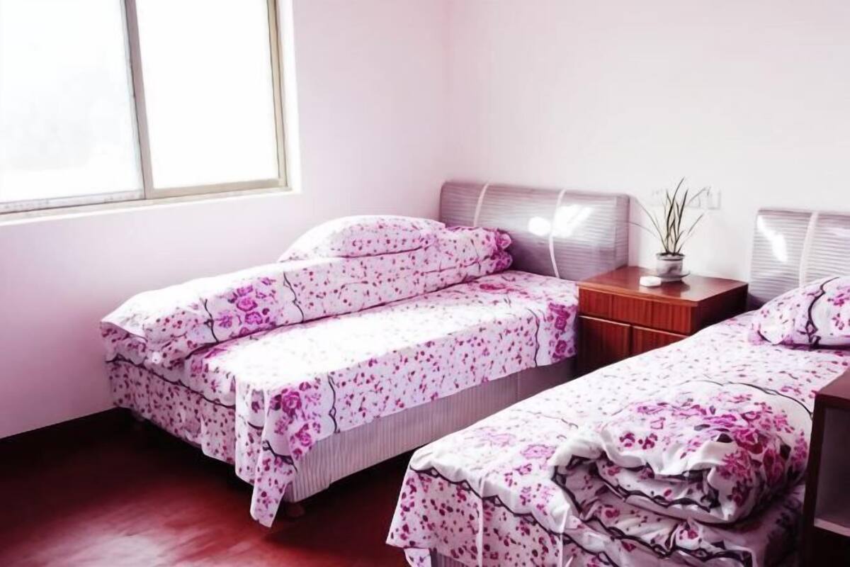 Une chambre avec deux lits, une table de chevet avec une lampe et une fenêtre.