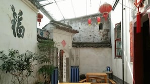 A courtyard with traditional Chinese architecture, including a tiled roof, wooden tables, and red lanterns. - Qingyuan Renjia Inn (Wuyuan)