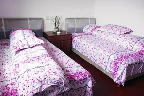 A room with two beds, a nightstand, and a potted plant. - Qingyuan Renjia Inn (Wuyuan)