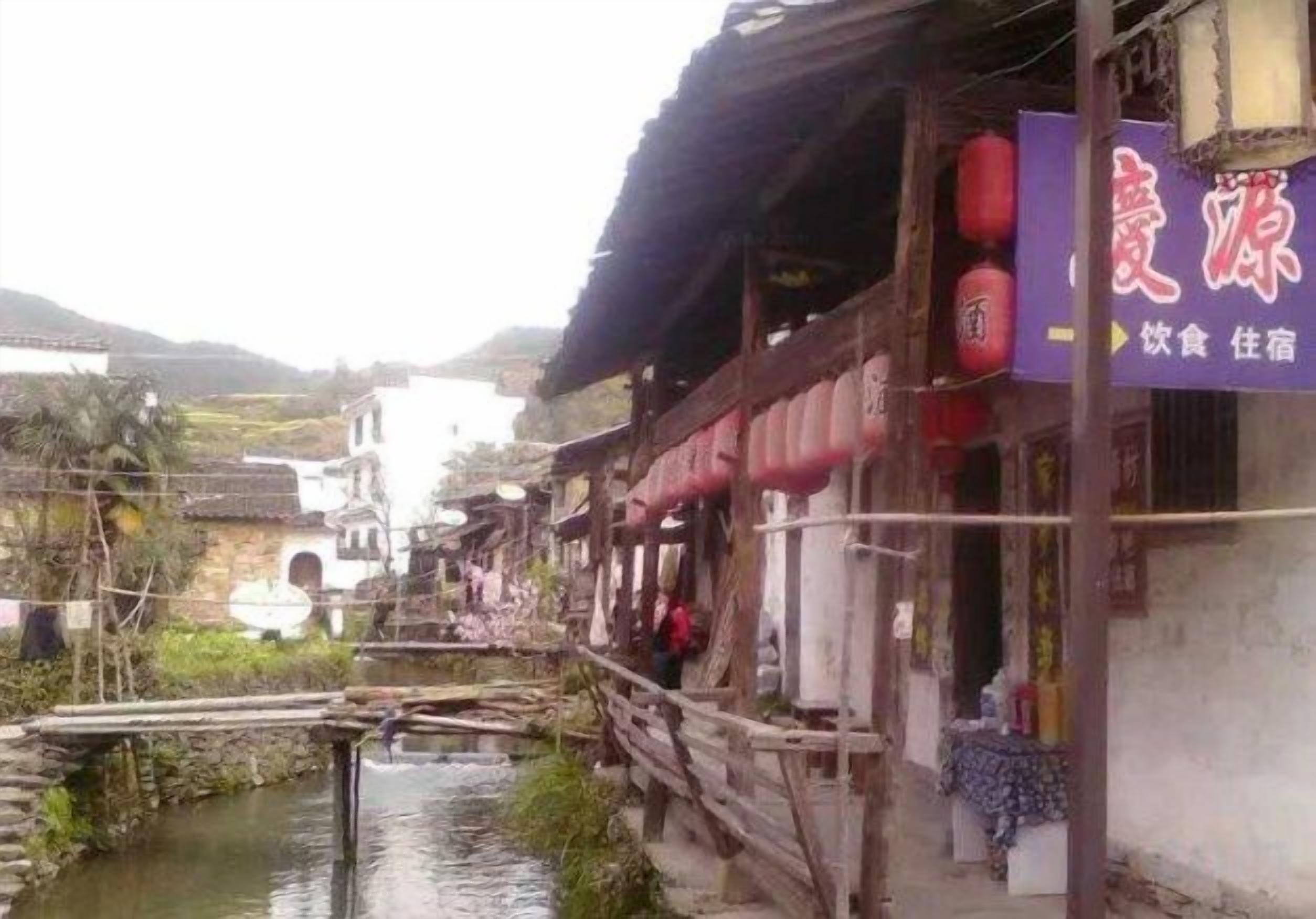 Un bâtiment traditionnel, avec une enseigne, un pont en bois et une rivière.