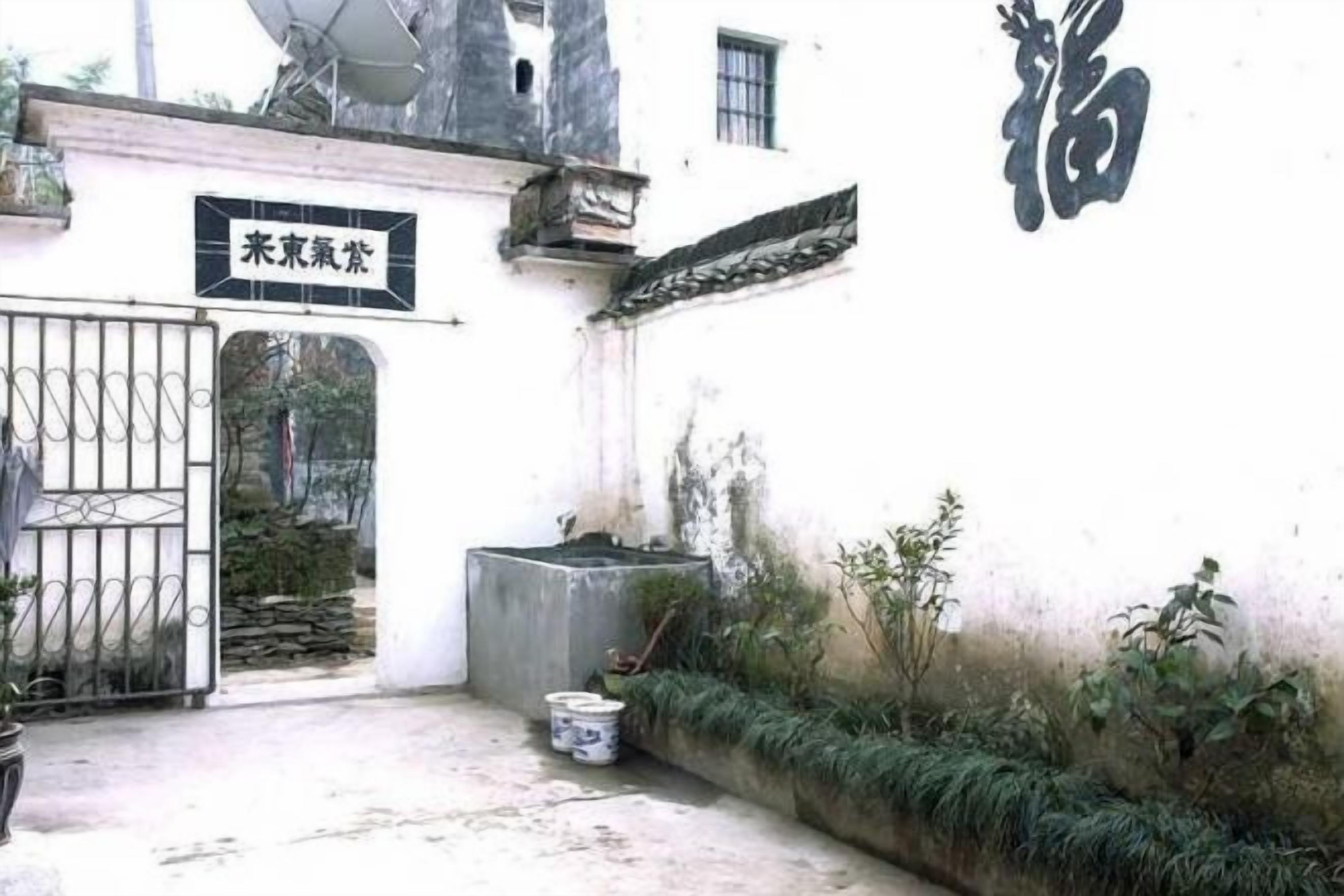 A gated entrance to a building with a sign above the gate and a wall with Chinese characters.