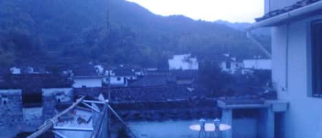 Terraza en la azotea con vistas a un pueblo, una barandilla y dos taburetes.