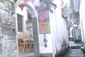 A narrow alleyway with a traditional building, a wooden chair outside, and a sign on the wall. - Qingyuan Renjia Inn (Wuyuan)